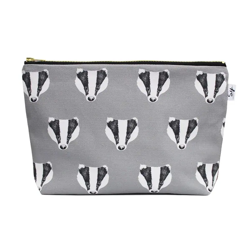 Badger wash bag: rows of black and white badger faces on grey cotton with a gold zip