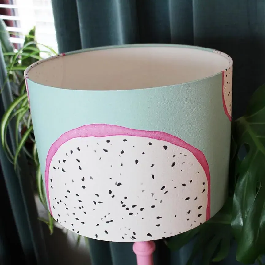 Dragon Fruit lampshade: a drum shade printed with dragon fruit halves, white with black seeds and pink rinds, on pale turquoise
