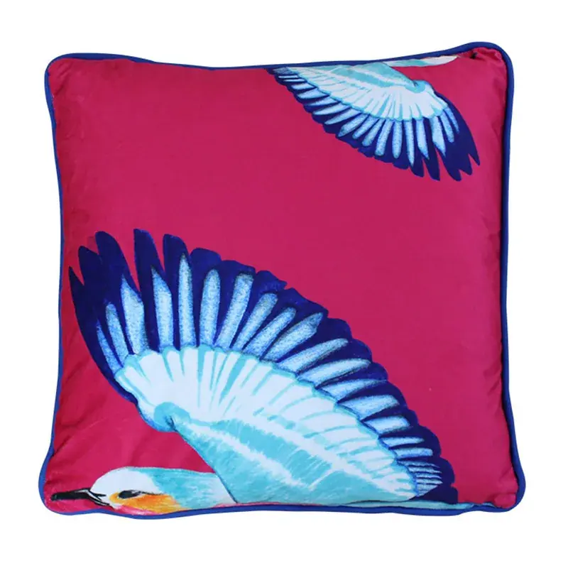 Safari Bird velvet cushion: a lilac-breasted roller swooping across cherry pink velvet with royal blue piping