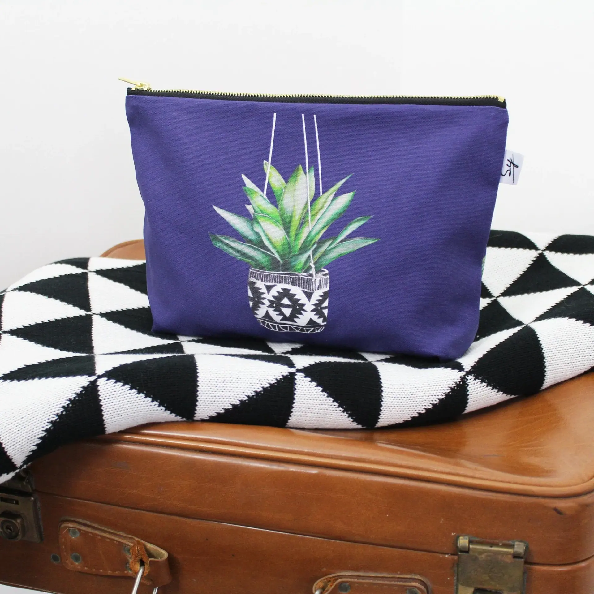 Succulent wash bag: a green succulent in an Aztec-patterned pot on purple cotton with a gold zip