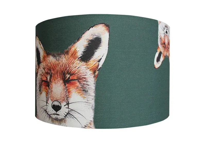 Urban Fox lampshade: a jade green drum shade with a hand-drawn dozing fox, and a second fox peeking round the curve