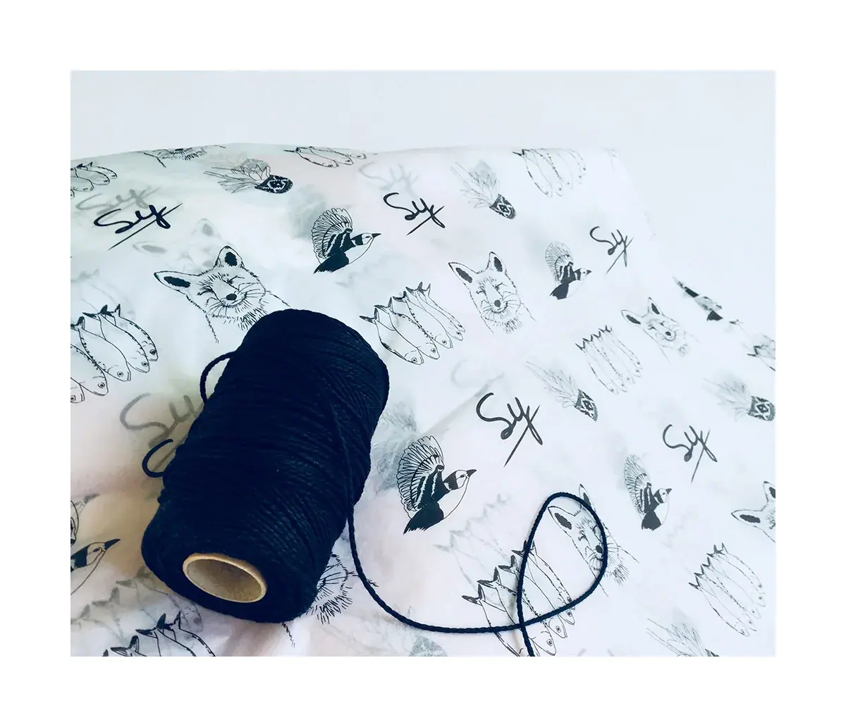 Compostable tissue paper printed with Rachael's line drawings of foxes, birds and succulents, with a spool of navy twine