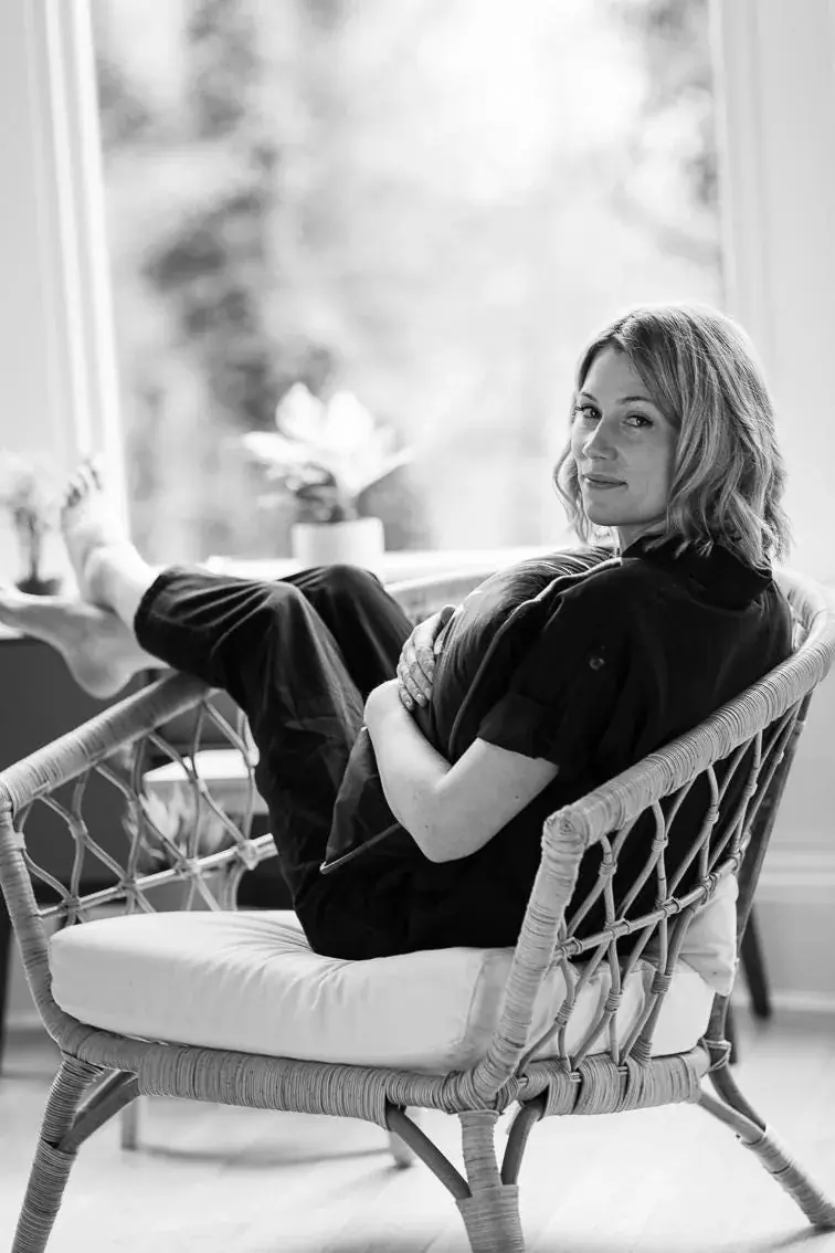 Rachael sitting in a rattan chair by a bright window