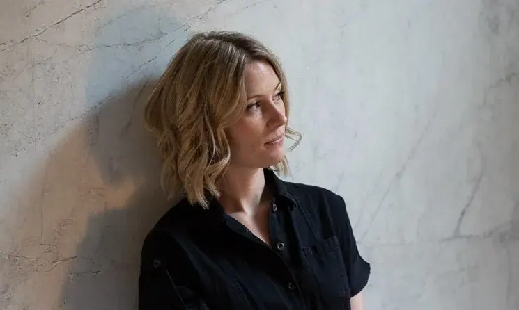 Rachael leaning against a pale marble wall