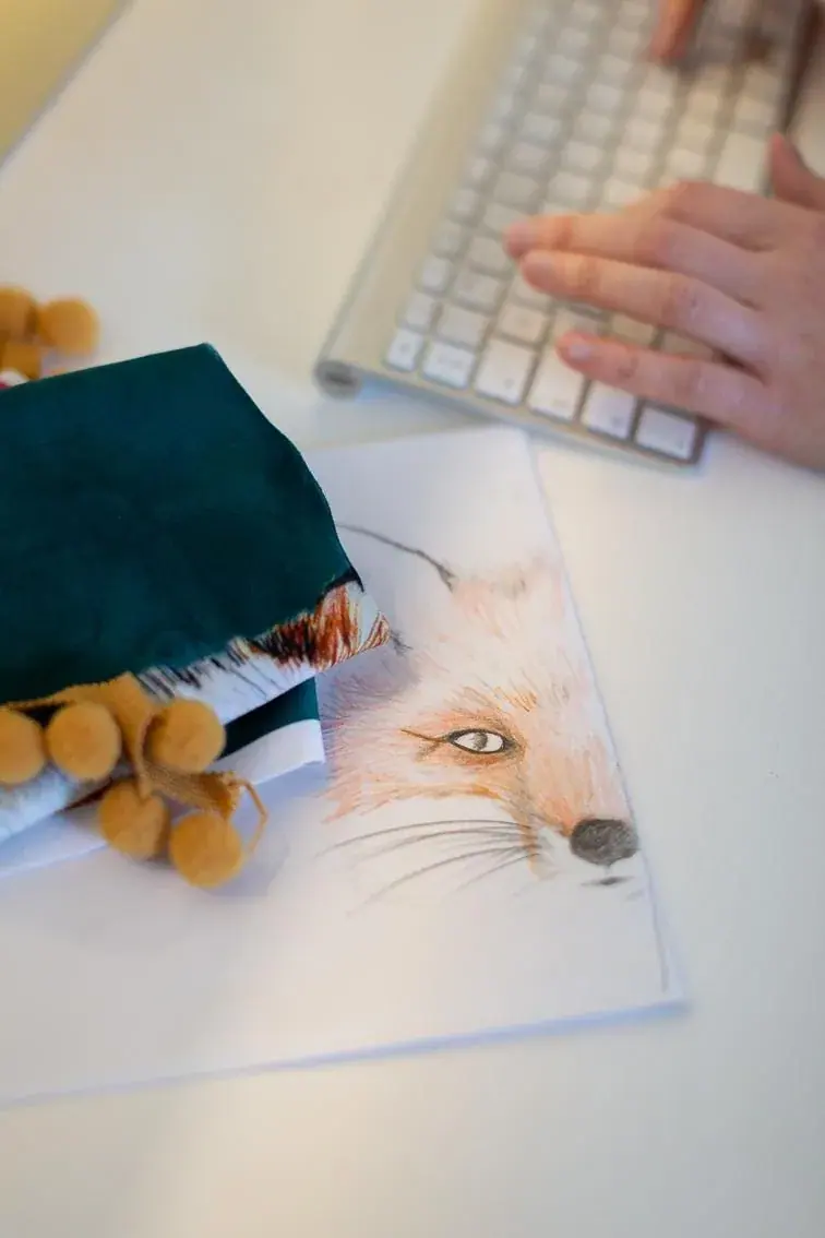 The Urban Fox illustration on Rachael's desk beside her keyboard and a velvet swatch